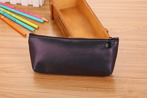 Vue détaillée de la trousse en cuir PU violet foncé avec fermeture sur bureau en bois