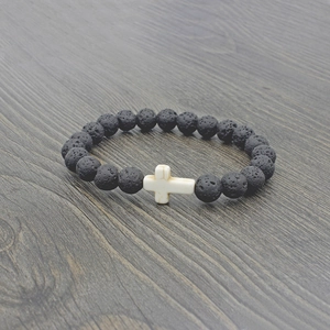 Macro shot of black volcanic lava beads and white stone cross detail on the beaded bracelet