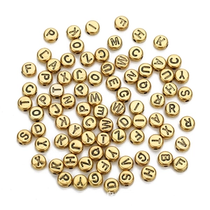 Close-up of gold acrylic round letter beads for DIY jewelry making on white background