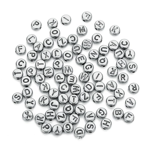 Macro shot of silver round flat acrylic alphabet beads with metallic luster for DIY