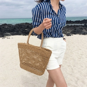 Close-up of a handmade straw tote bag with hollow woven mesh design for beach vacation