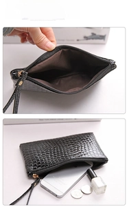 Macro view of black crocodile pattern clutch bag internal structure and daily essentials