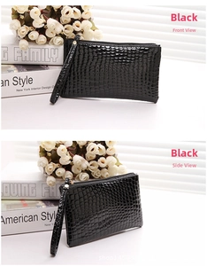 Detail view of black crocodile pattern leather clutch bag with wristlet and zipper