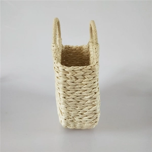Detailed close-up of handmade beige straw handbag showing natural woven texture and handles