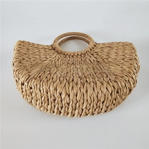 Close-up of the textured semi-circle woven straw handbag with a round handle detail