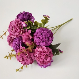 Detailed top view of purple and rose red hydrangea silk flower heads with green leaves