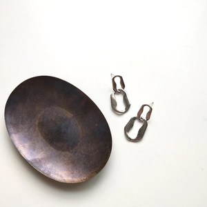 Detailed view of silver 925 geometric earrings on a vintage metal tray with white background