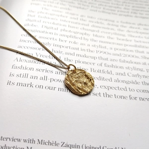 Macro detail of 925 sterling silver golden coin pendant on a textured book background