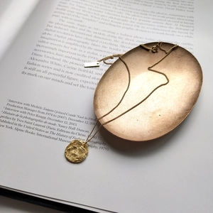 Detail of a gold plated 925 silver necklace with coin pendant and rectangular tag