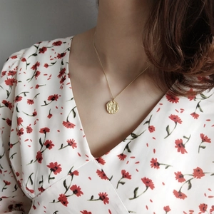 Detail of 925 sterling silver gold coin pendant necklace on model with floral shirt