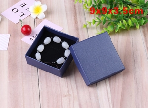 Blue linen jewelry box 9x9x3.5cm featuring a pearl bracelet inside on wood background
