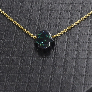 Detailed view of Hamsa Hand pendant with green and blue opal on gold necklace
