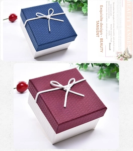 Detail of square jewelry gift box with ribbon bow and textured lid in blue and red
