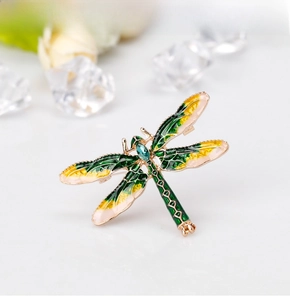 Macro detail of enamel dragonfly brooch with gold metal wings and blue teardrop gem