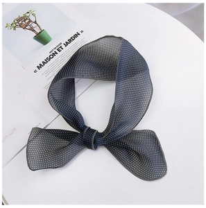 Détail d'un foulard en soie bleu à pois noué en nœud sur un magazine élégant