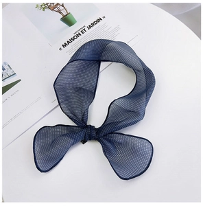 Gros plan d'un foulard en mousseline bleu marine à pois blancs avec coutures délicates