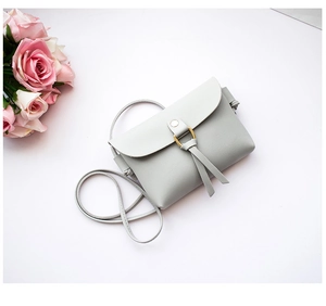 Close-up of a mini crossbody bag with a golden ring buckle and leather tassels