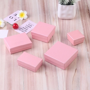 Set of pink textured paper jewelry gift boxes in various sizes on a clean wooden background