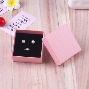 Pink textured jewelry gift box with white pearl earrings and silver diamond ring inside