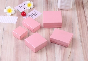 Pink linen textured jewelry gift boxes in various sizes on a rustic wood background