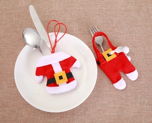 Flat lay of Santa clothes and trousers cutlery holders on white plates with silver utensils