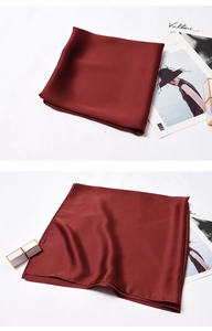 Detailed view of burgundy satin scarf texture and elegant sheen on white backdrop