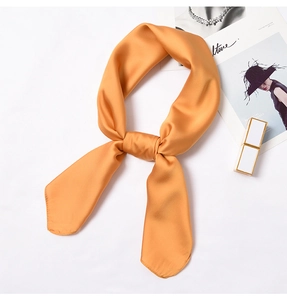 Detail of bright orange silk square scarf showing smooth texture and rolled edges
