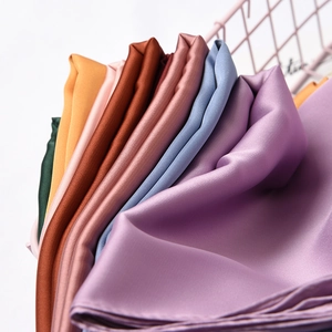 Elegant solid color satin square silk scarves displayed in a modern pink wire basket