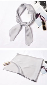 Detail of silver gray satin square scarf showing smooth silk texture and knotted styling