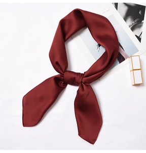 Detail of burgundy satin neck scarf with elegant knotting and smooth silk-like texture