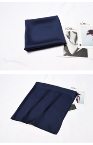Detail of dark blue silk scarf showing smooth satin texture and premium hemmed edges