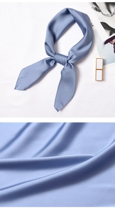 Detail of blue satin neck scarf showing glossy silk texture and elegant tied knot