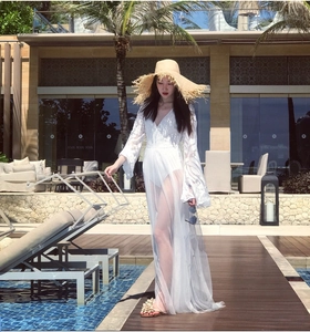 Elegant white lace beach cover-up with long flared sleeves and V-neck by a resort pool