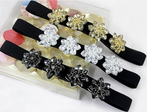 Detail of crystal flower elastic waist belts in gold, silver, and black finishes