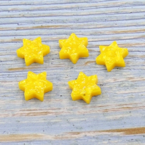 Five yellow synthetic opal Star of David charms with gold foil glitter on wood background
