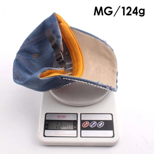 Detail view of denim baseball cap weighing 124g on a scale with rhinestone brim