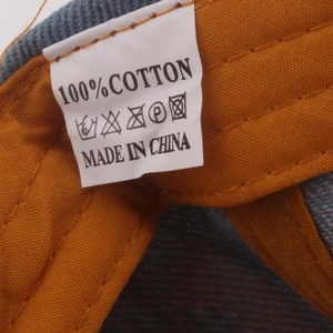 Detail view of the 100% cotton material tag and wash care label inside the baseball cap
