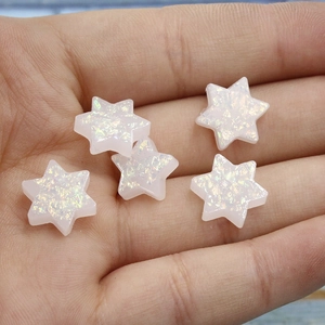 Detailed view of five white synthetic opal Star of David charms held in hand