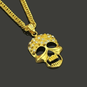 Goldene Totenkopf-Halskette mit Panzerkette und Strasssteinen auf dunklem Hintergrund