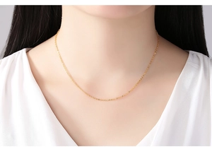 Close-up of minimalist 14K gold plated water wave chain necklace worn by a model