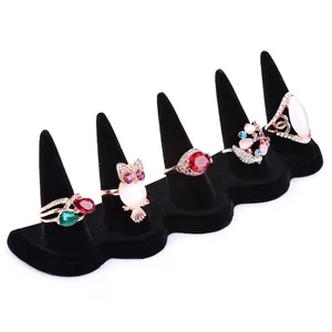 Detail view of five gold-plated rings with assorted gemstones on black velvet finger display