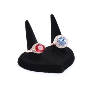Detail of red and blue gemstone rings with diamond halo on black velvet heart display