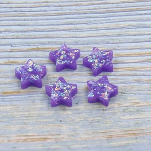 Close-up of five purple star-shaped resin opal beads with iridescent glitter for DIY jewelry