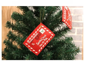 Red felt Christmas envelope ornament hanging on a tree with festive Santa mail design