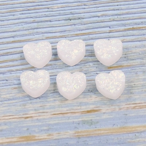 Macro detail of six 12mm heart-shaped white synthetic fire opal stones on blue wood