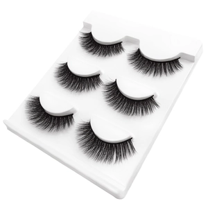 Macro detail of three pairs of voluminous black 3D false eyelashes on a white tray