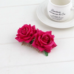 Detail of red rose hair comb with golden metal prongs on white wood background
