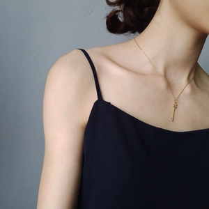 Close-up of elegant 925 sterling silver gold-plated key pendant necklace on female model