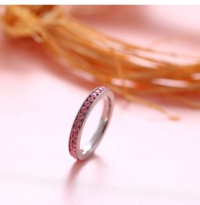 Detailed macro view of silver ring band with channel-set pink gemstones and polished finish