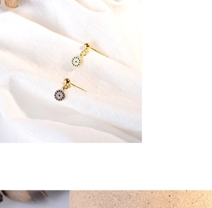 Macro shot of gold Evil Eye earrings with sparkling blue and white crystal inlay